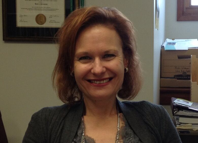 A woman sits at her desk smiling.