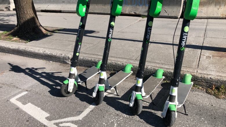 Lime e-scooters parked on a road. 