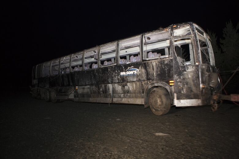 the wreck of a bus that fatally crashed, blackened and all windows gone. It has the word 