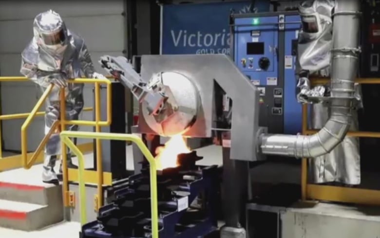 A person in a silver protective suit works inside an industrial facility.