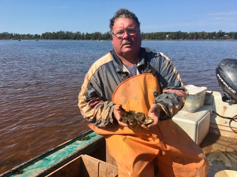 Bob MacLeod, in his fishing boat, holds a handful of oysters.