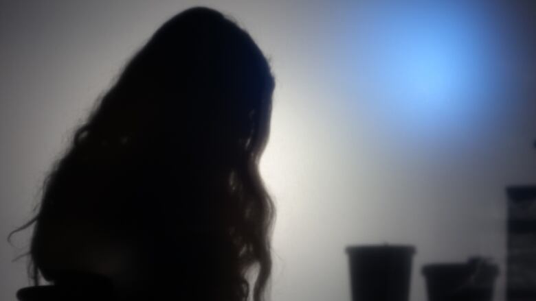 A silhouuette photo of a woman, kept undistiguishable to protect her identity.