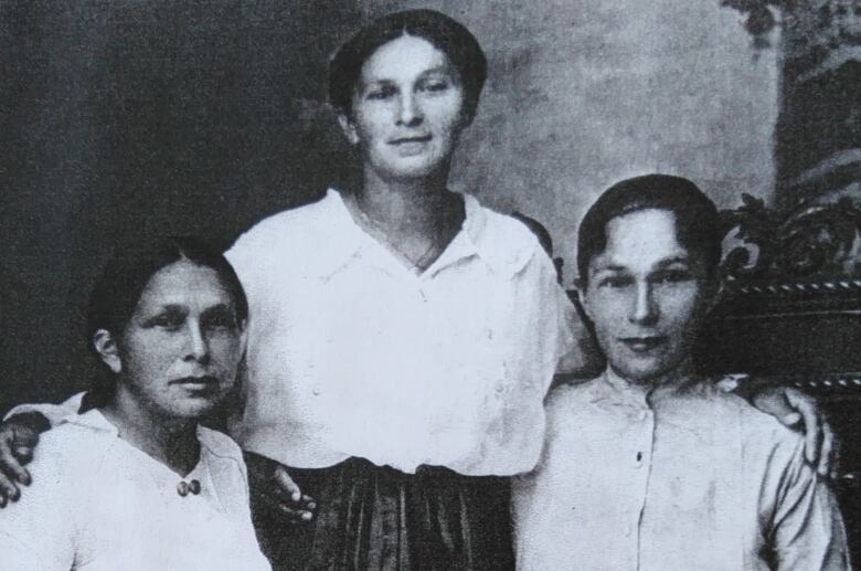 Three women smile for the camera in a black-and-white picture.