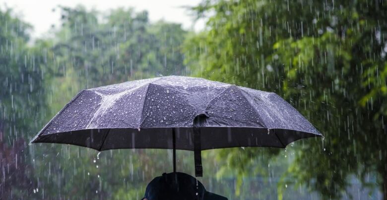 An umbrella is held up for protection in heavy rain. 