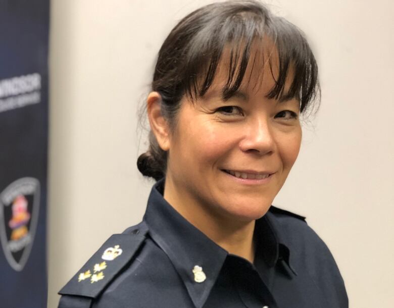 Pam stands in front of a windsor police logo