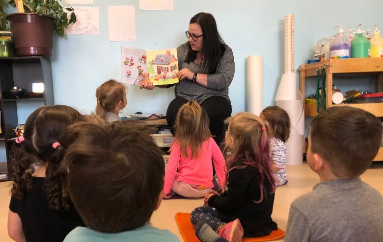 A woman reading a book to young children.