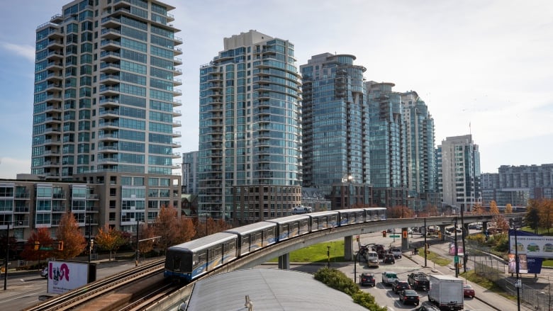 A SkyTrain passes by a series of condos.