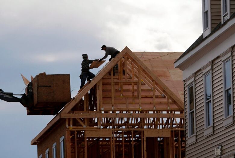 Construction workers work on the roof of a new townhouse.