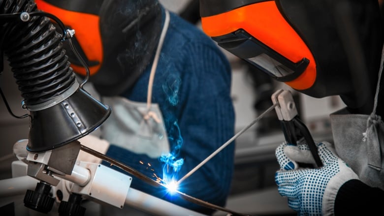 A person in a mask welds.