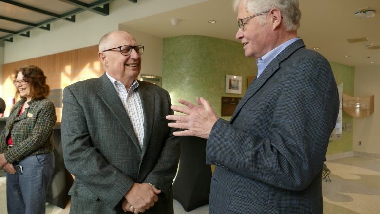 Two men in suits share a conversation.