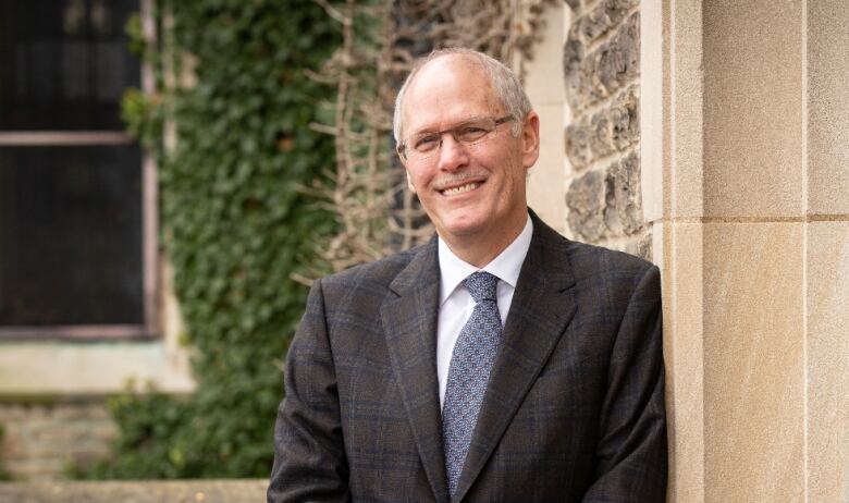 A portrait of a man in a suit outside.