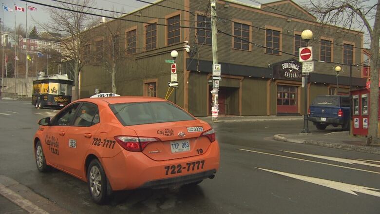 An orange taxi parked on a downtown street. 