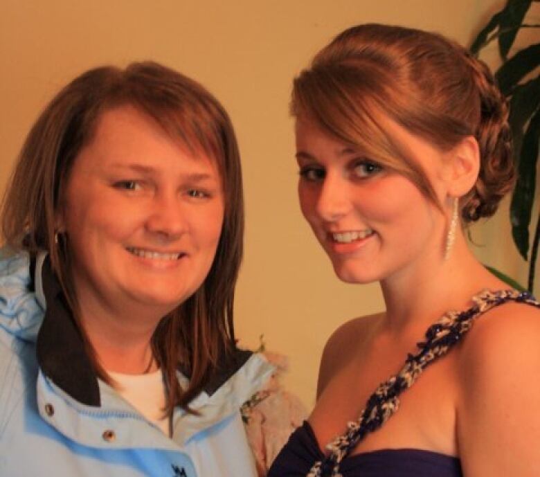 Two woman stand side by side and smile. 