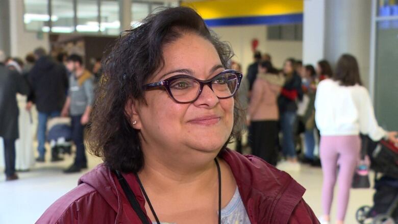 A woman with looks slightly off camera. She has dark hair cut into a bob haircut and she's wearing glasses. 