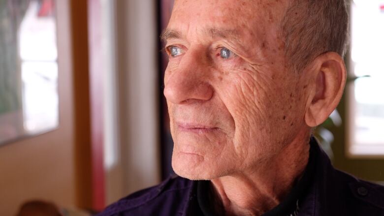 Close up of a man's face, from the profile. He's older, with wrinkles and liver spots and thin, grey hair.