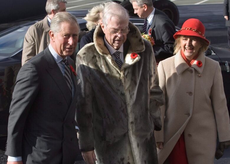 Three people walk through a parking lot. 