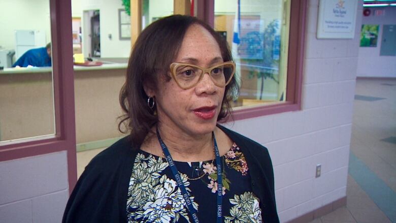 A Black woman wearing beige glasses, a cardigan and a blouse