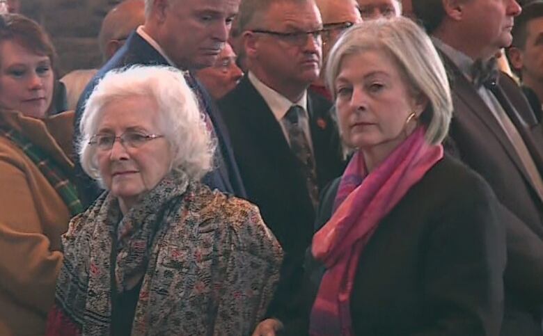 Two women walk through a church. 