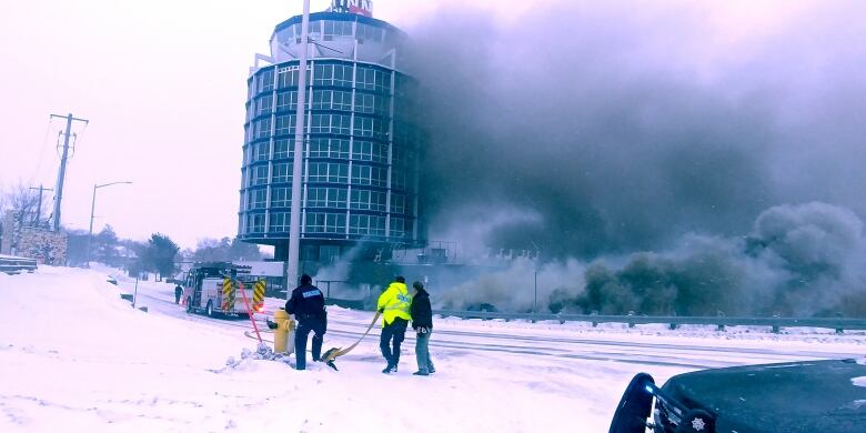 The 9-story circular building with smoke billowing up from it's right side reaching all the way to the top of the building. 