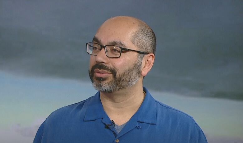 A man with a beard wearing a blue polo shirt.