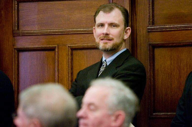 Prime Minister Stephen Harper's Chief of Staff, Ian Brodie watches from the back of the room, a photo-op before the government caucus meeting on Parliament Hill in Ottawa Wednesday March 5, 2008.