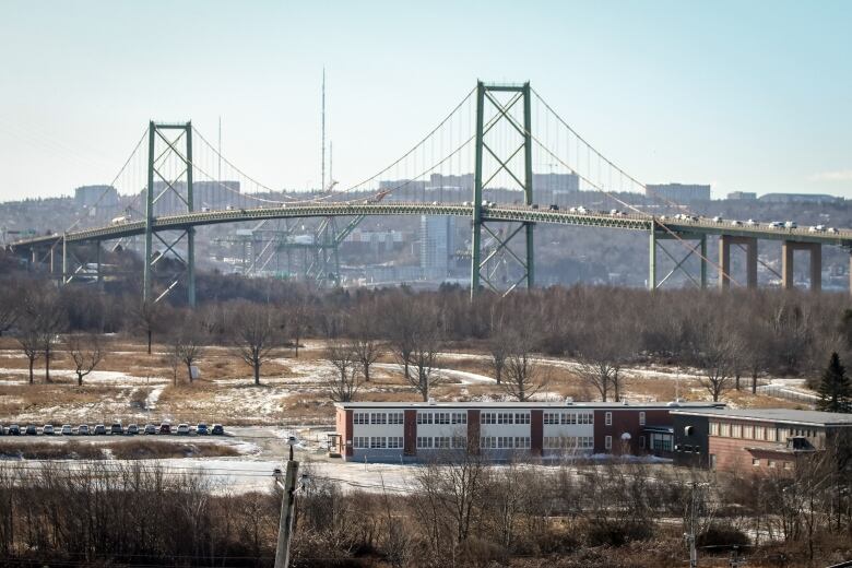 A steel truss bridge, with a low-rise building in the foreground.