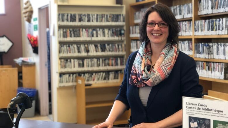 A woman with a colourful scarf stands at a library counter