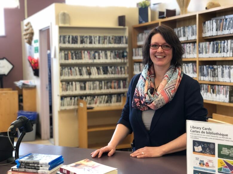 A woman with a colourful scarf stands at a library counter