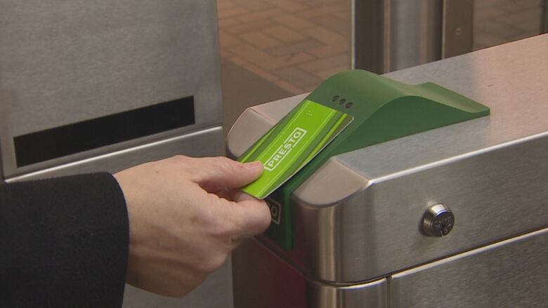 A person tapping a Presto card on a reader.