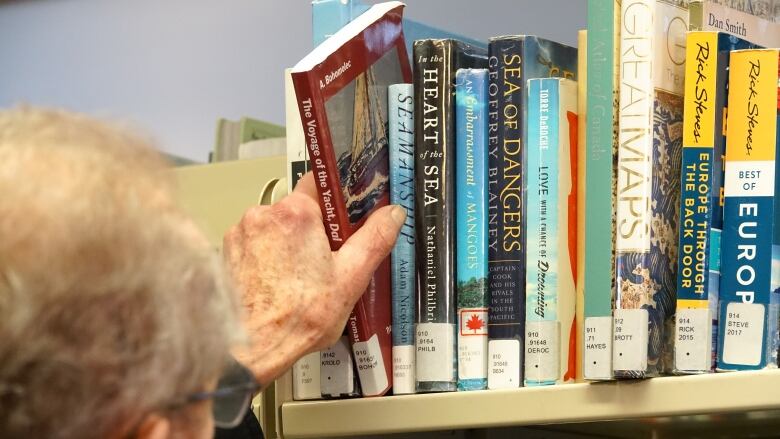 A man grabs a book of a shelf