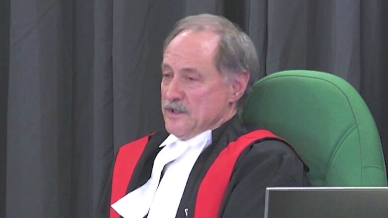 Judge wearing robes is seen presiding over an inquiry.