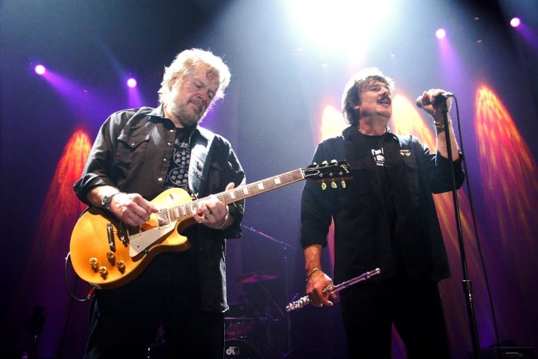 A guitarist and singer are pictured performing on stage.