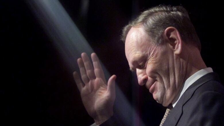 A politician waves in the spotlight.