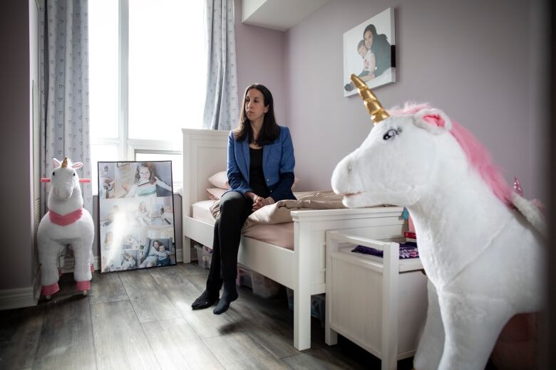 A mother sits on her daughter's bed. Two stuffed are displayed on her sides.