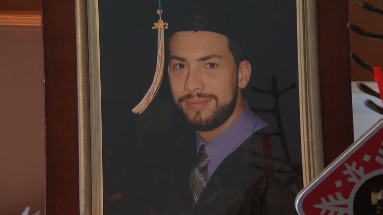 Graduation photo of young man with beard and mustache. 