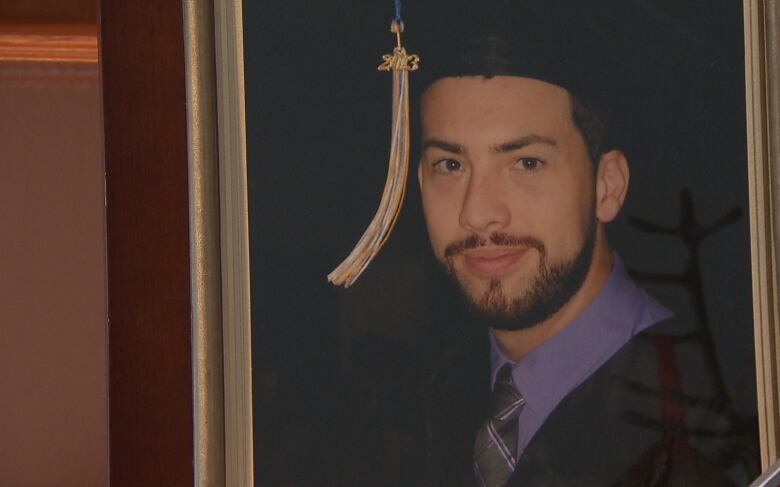 Graduation photo of young man with beard and mustache. 