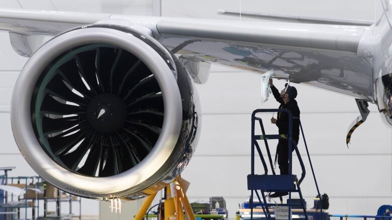 An Airbus employee works under the wing of an Airbus A220 at the assembly plant in Mirabel, Que., Feb. 20, 2020. 