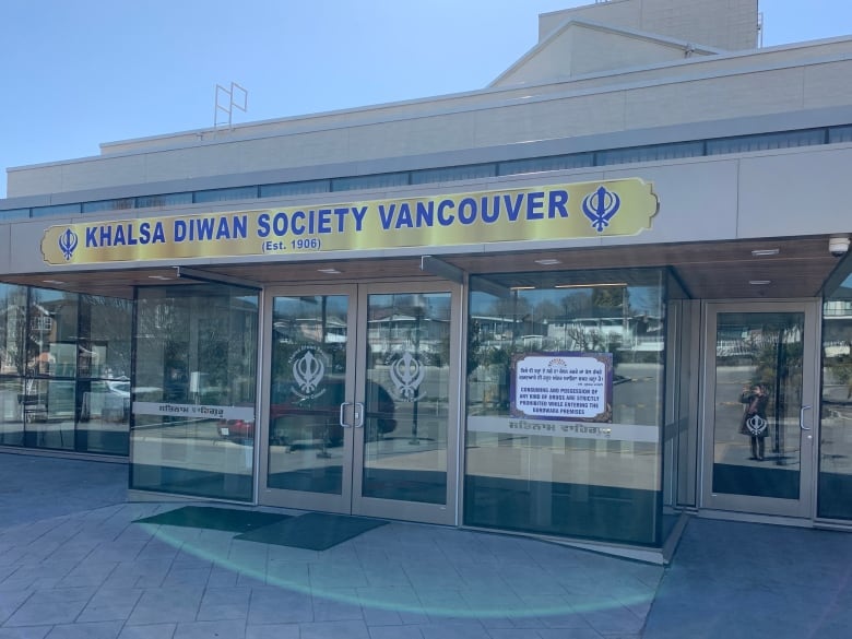 A brown building with a glass front and a sign that reads 'Khalsa Diwan Society Vancouver.'