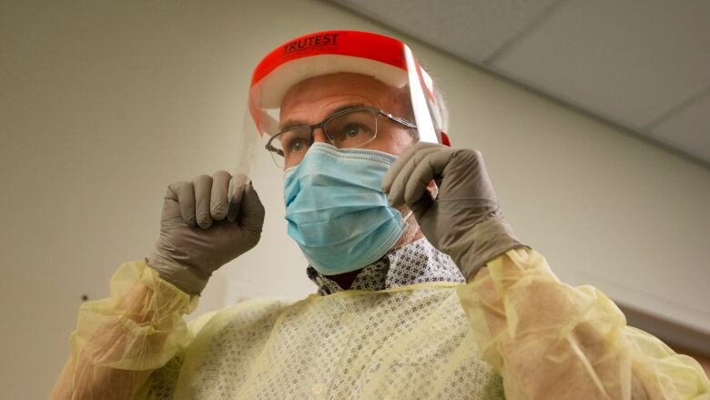 An employee at the COVID-19 screening clinic at Montreal's old Htel-Dieu Hospital illustrates how to put on protective equipment.