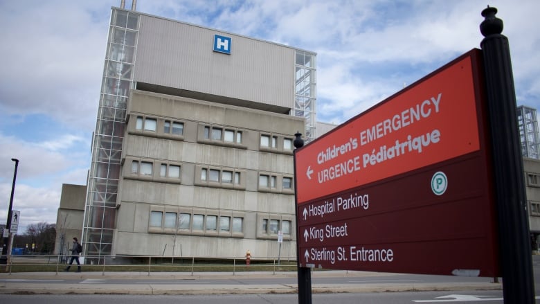 A hospital seen from across a road, with a sign reading 