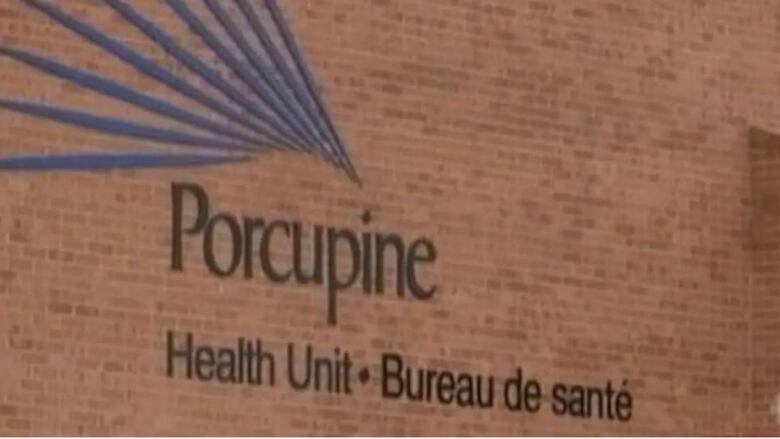 The blue text of the Porcupine Health unit sign hangs on a red brick wall.