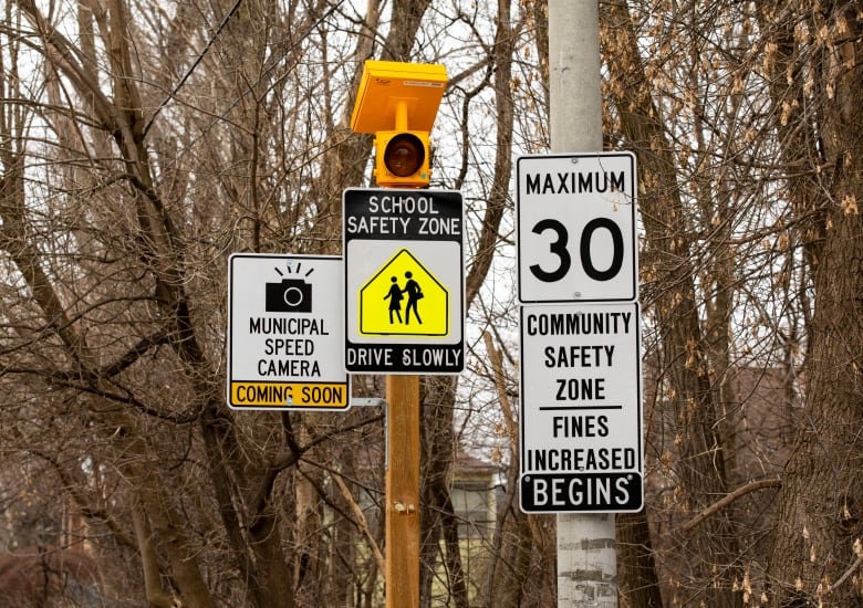 A municipal speed zone sign in Toronto with trees behind it.