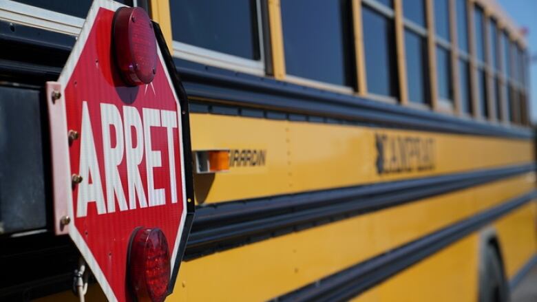 A school bus is shown from the side. The red stop sign is in French and reads 