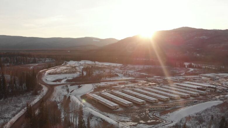 Workers' lodges sit underneath a setting sun in winter.