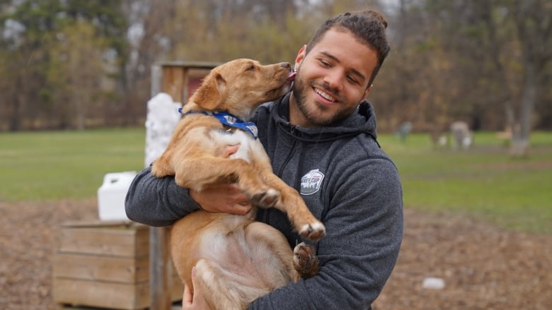 A man holds a dog in his arms as the pooch gives him a kiss on the cheek.