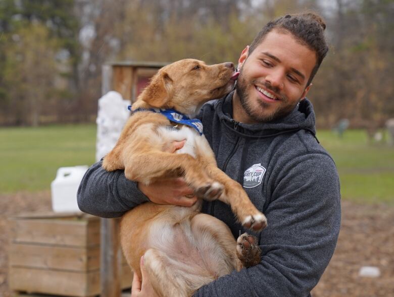 A man holds a dog in his arms as the pooch gives him a kiss on the cheek.