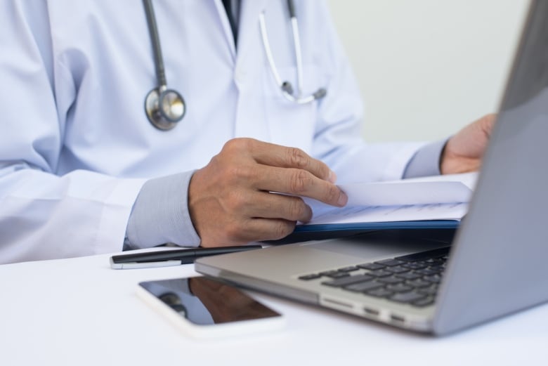 A stock image of a physician sitting at a lap computer.