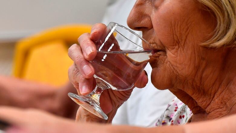 A woman drinking water from a glass.