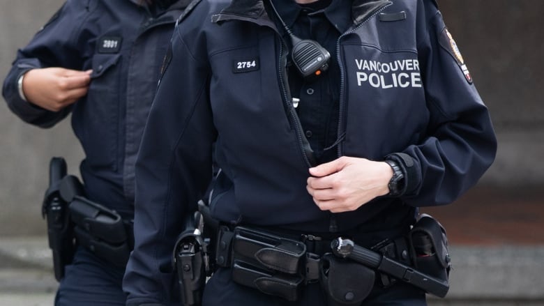 A close up picture of two Vancouver Police officers with jackets and walkie-talkies on their chests.