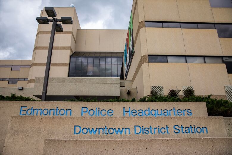 A large concrete building with black windows is shown. A sign on the property reads, Edmonton Police Headquarters, Downtown District Station. 